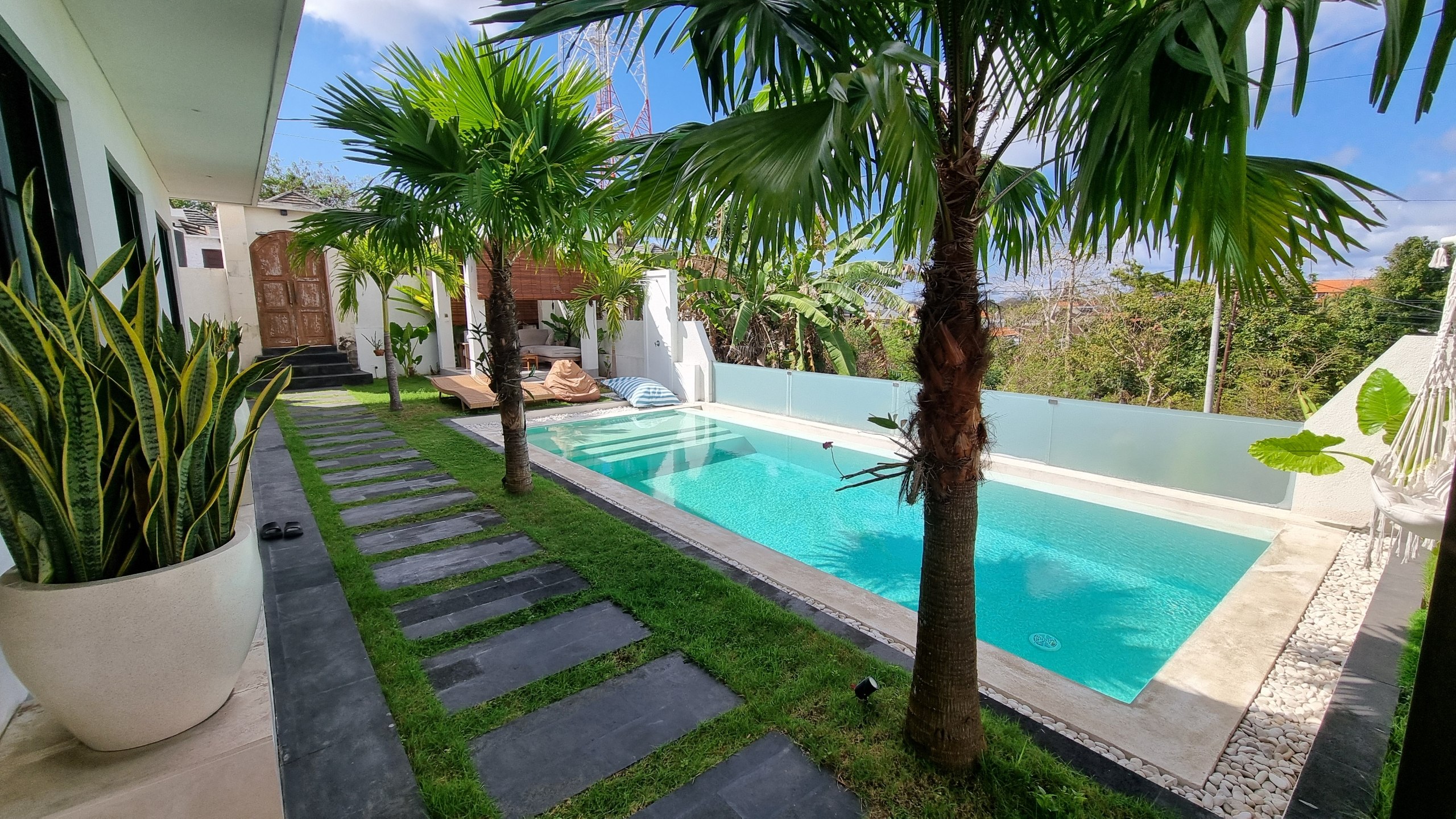 Pool framed by palm trees and a stepping-stone garden path